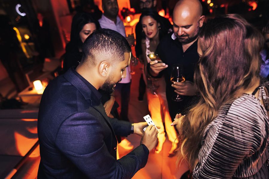 Close-up magic at an evening event, captivated guests